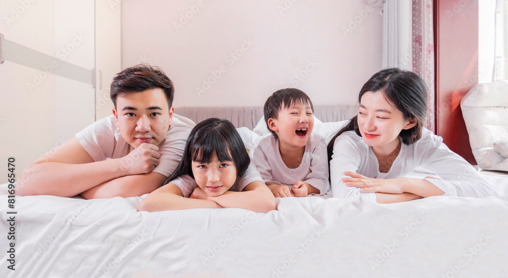 Fototapeta premium A family of four in bed in the bedroom