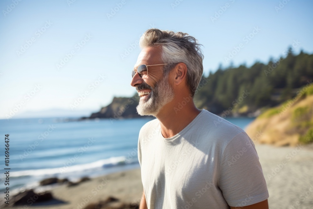 Portrait of a happy man in his 50s laughing over soft teal background