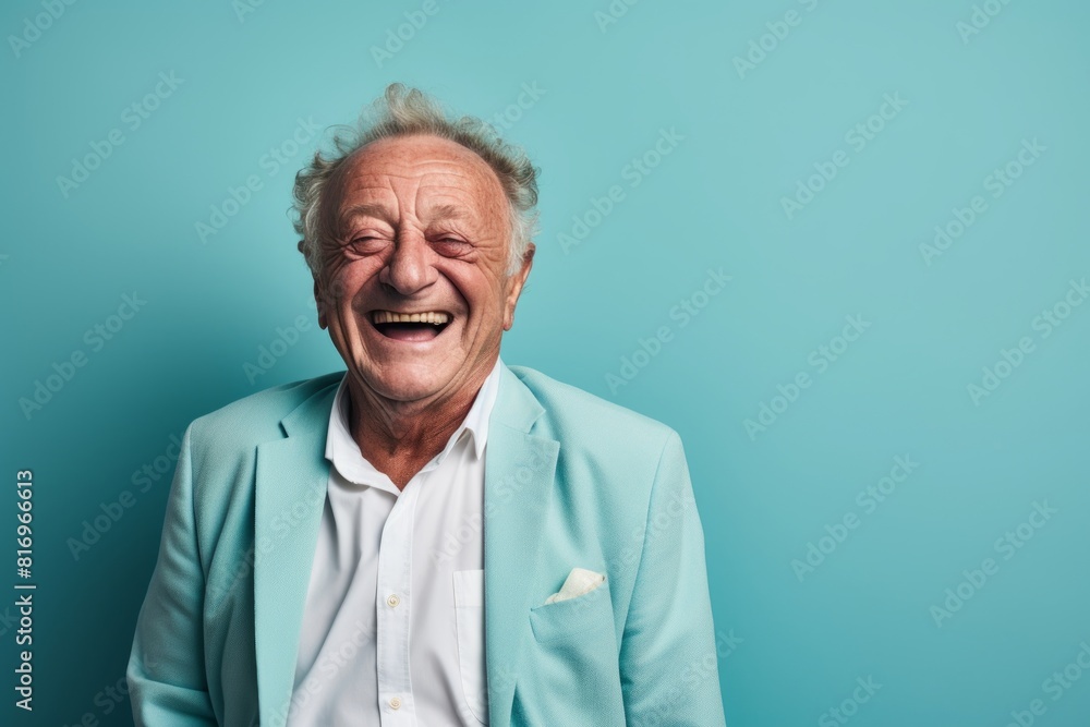 Portrait of a satisfied man in his 80s laughing in soft teal background Portrait of a satisfied man in his 80s laughing in soft teal background