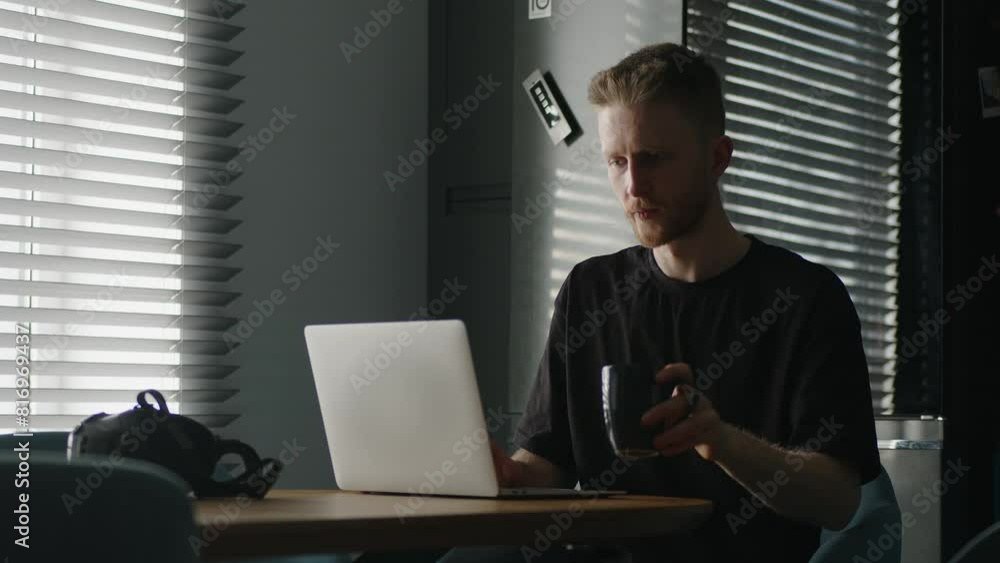 A man works on a laptop at home in the kitchen in the morning. A man works on a laptop at home in the kitchen in the morning.