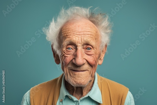 Portrait of a happy elderly 100 years old man smiling at the camera in front of soft teal background © Markus Schröder