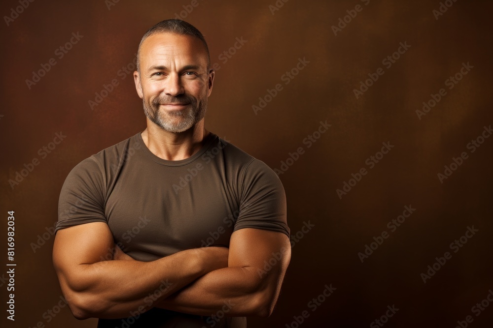 Portrait of a happy man in his 40s with arms crossed on soft brown background