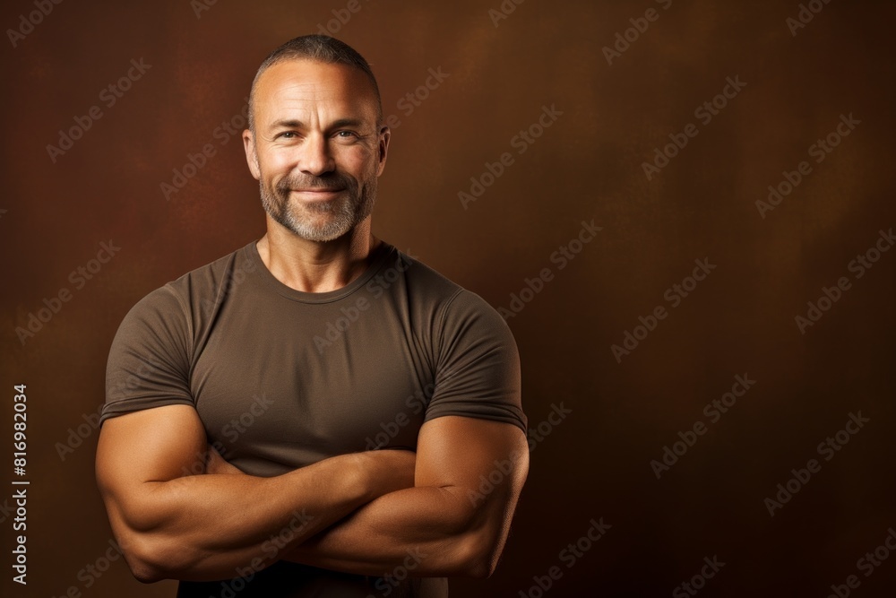 Portrait of a happy man in his 40s with arms crossed on soft brown background Portrait of a happy man in his 40s with arms crossed on soft brown background