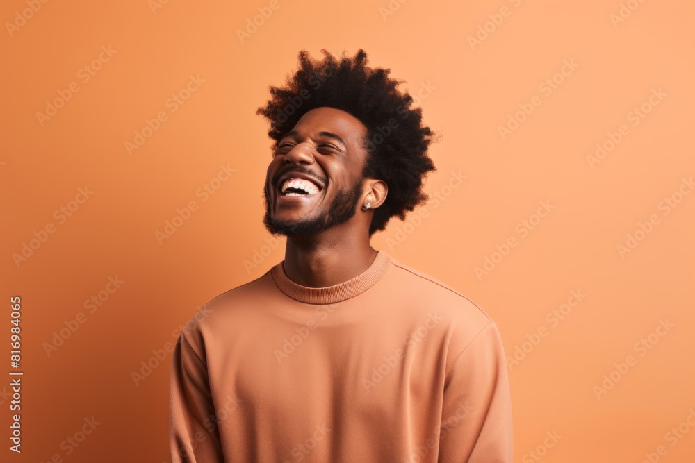 Portrait of a blissful afro-american man in his 20s laughing isolated on soft brown background Portrait of a blissful afro-american man in his 20s laughing isolated on soft brown background