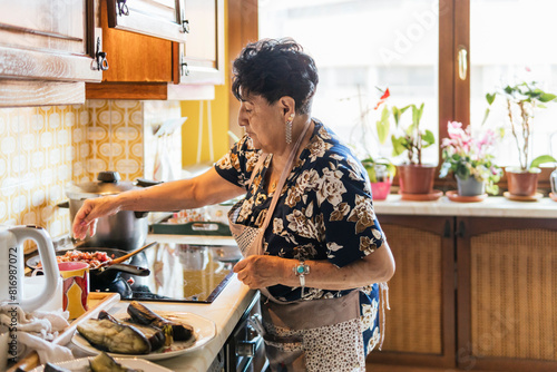 Elderly woman preparing a meal in her kitchen photo