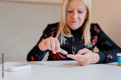 Mature woman testing blood sugar level at home photo