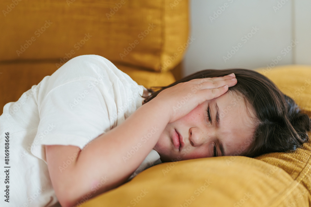 Young girl experiencing headache while resting on couch Young girl experiencing headache while resting on couch