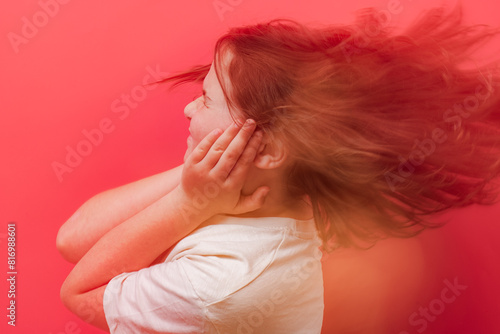 Young child feeling dizziness with hands on head against red background photo