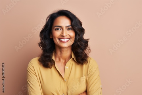 Portrait of a content indian woman in her 40s smiling at the camera while standing against pastel or soft colors background © Markus Schröder