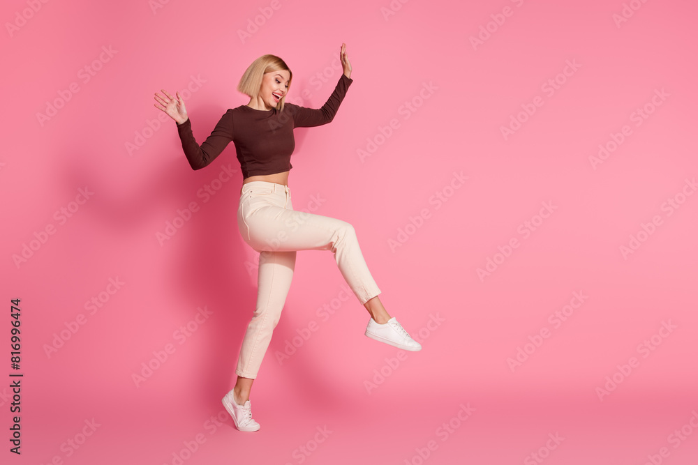 Photo of cheerful adorable girl wear stylish brown clothes go climb empty space isolated on pink color background Photo of cheerful adorable girl wear stylish brown clothes go climb empty space isolated on pink color background