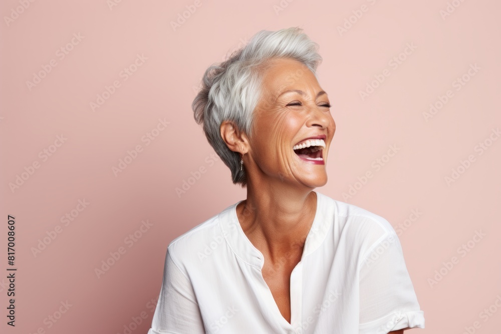 Portrait of a smiling woman in her 60s laughing isolated in pastel or soft colors background Portrait of a smiling woman in her 60s laughing isolated in pastel or soft colors background