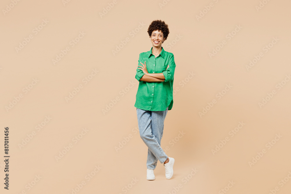 Full body young smiling woman of African American ethnicity she wear green shirt casual clothes hold hands crossed folded look camera isolated on plain pastel light beige background Lifestyle concept Full body young smiling woman of African American ethnicity she wear green shirt casual clothes hold hands crossed folded look camera isolated on plain pastel light beige background Lifestyle concept