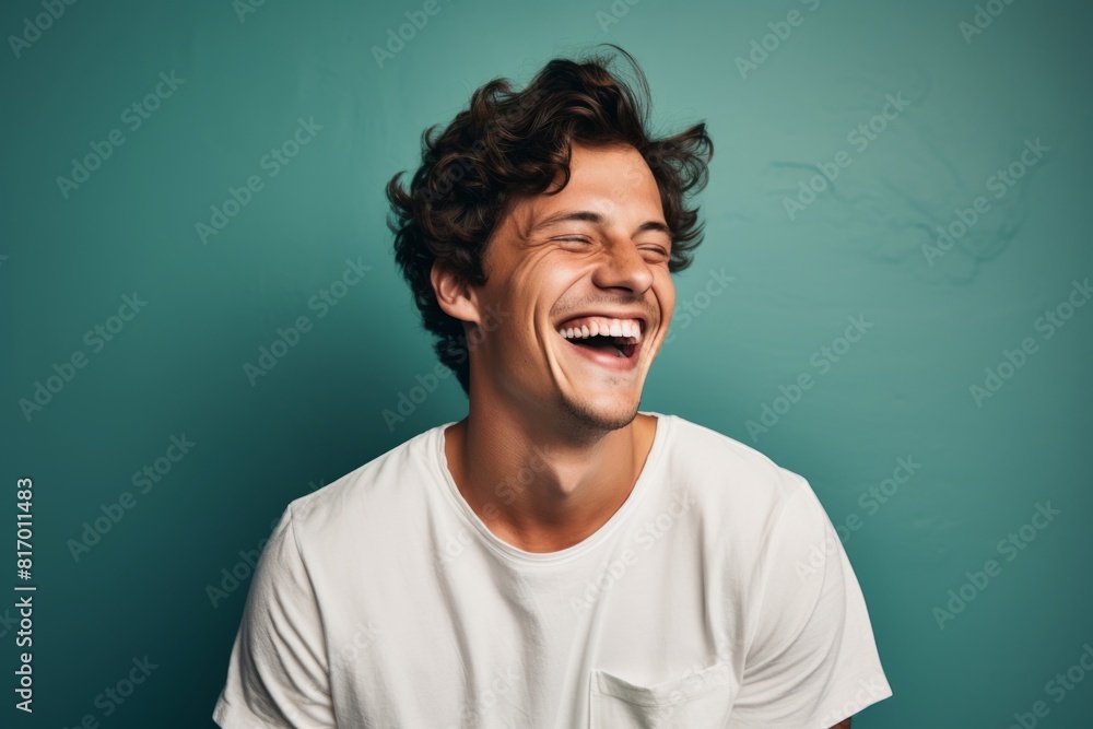 Portrait of a tender man in his 20s laughing while standing against pastel or soft colors background Portrait of a tender man in his 20s laughing while standing against pastel or soft colors background