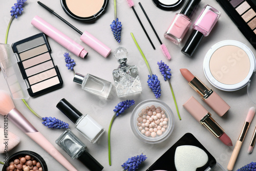 Flat lay composition with different makeup products and beautiful spring flowers on gray background