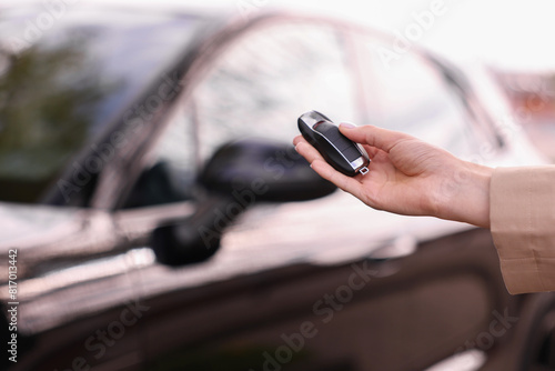 Woman holding car flip key near her vehicle outdoors, closeup