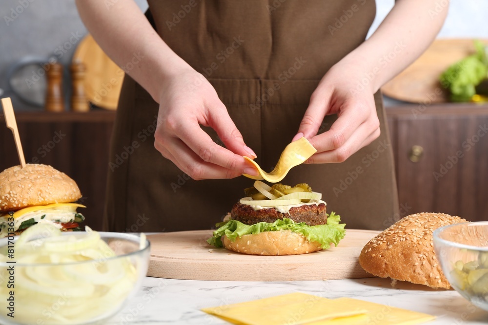 Woman making delicious vegetarian burger at white marble table, closeup Woman making delicious vegetarian burger at white marble table, closeup