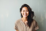 Portrait of a content asian woman in her 30s smiling at the camera over minimalist or empty room background