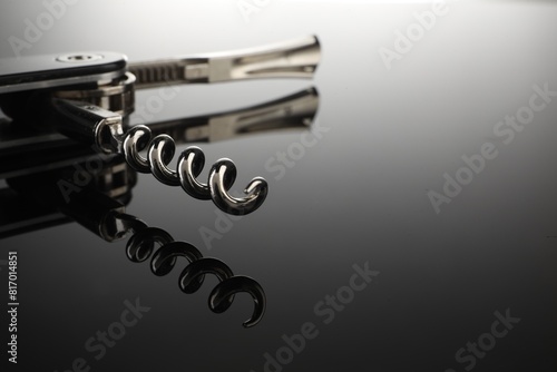 One corkscrew (sommelier knife) on mirror surface, closeup. Space for text photo