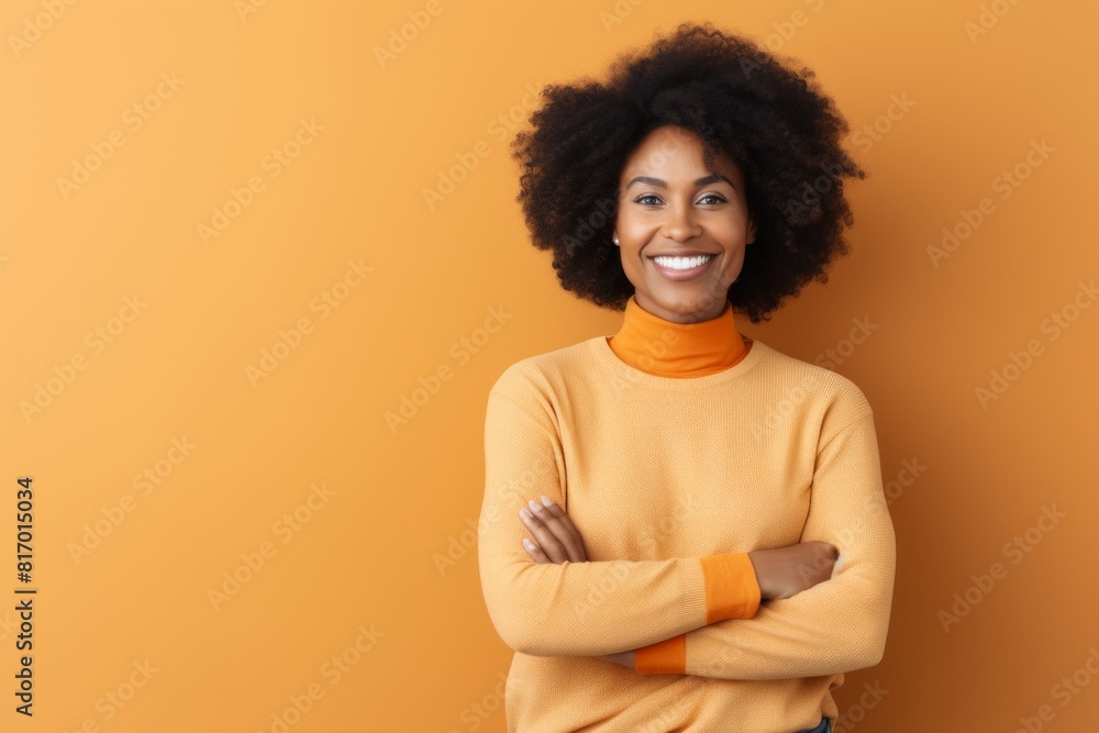 Portrait of a smiling afro-american woman in her 30s with arms crossed while standing against minimalist or empty room background Portrait of a smiling afro-american woman in her 30s with arms crossed while standing against minimalist or empty room background
