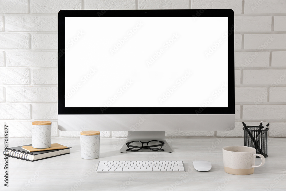 Fototapeta premium Office workplace with computer, cup and stationery on light table near white brick wall