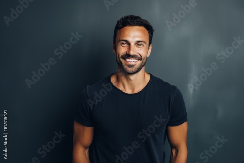 Portrait of a happy man in his 30s smiling at the camera while standing against minimalist or empty room background