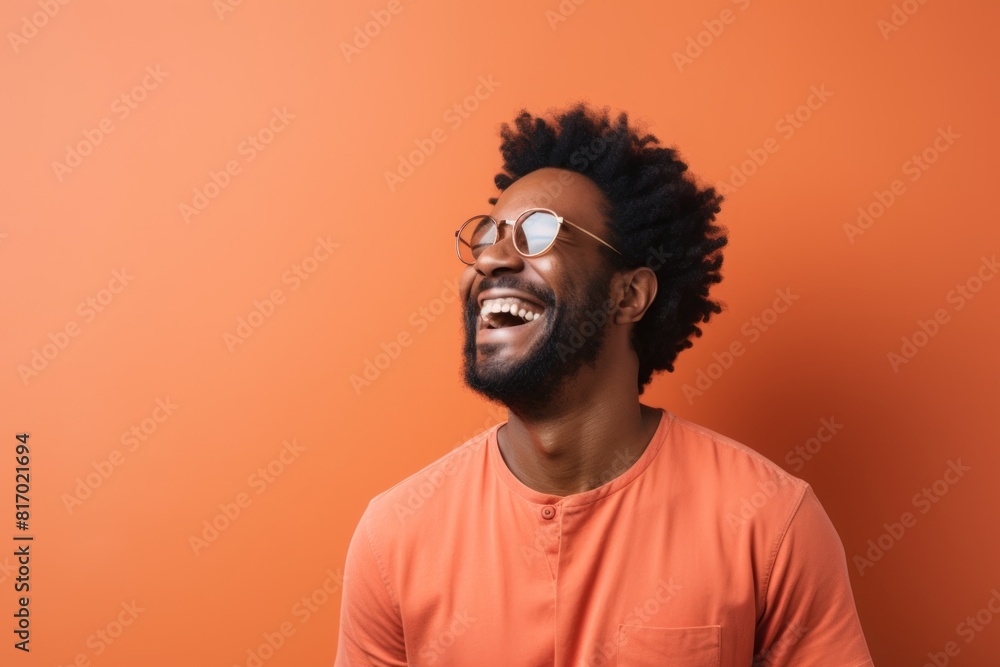 Portrait of a merry afro-american man in his 30s laughing on minimalist or empty room background Portrait of a merry afro-american man in his 30s laughing on minimalist or empty room background
