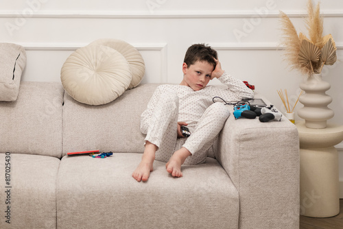 Boy lounging on couch with toys and game controller photo