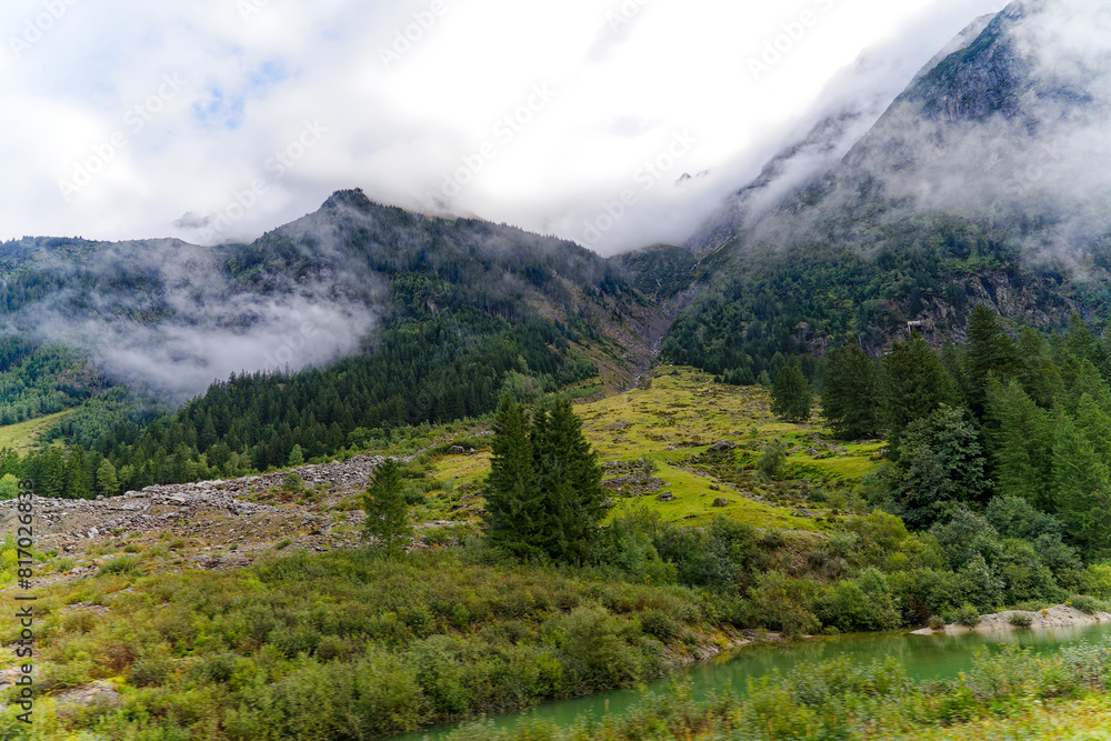 Obraz premium Alpine landscape in the Swiss Alps with fog and peak at mountain pass Grimsel on a cloudy late summer day. Photo taken September 19th, 2023, Grimsel, Canton Bern, Switzerland.