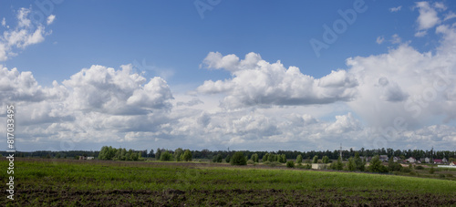 Panorama with beautiful and white clouds over a green field