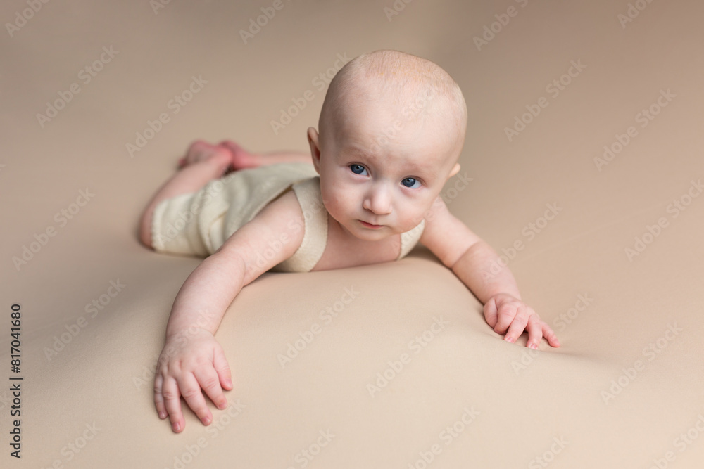 a small child lies on a light background. newborn boy. baby's first photo shoot a small child lies on a light background. newborn boy. baby's first photo shoot