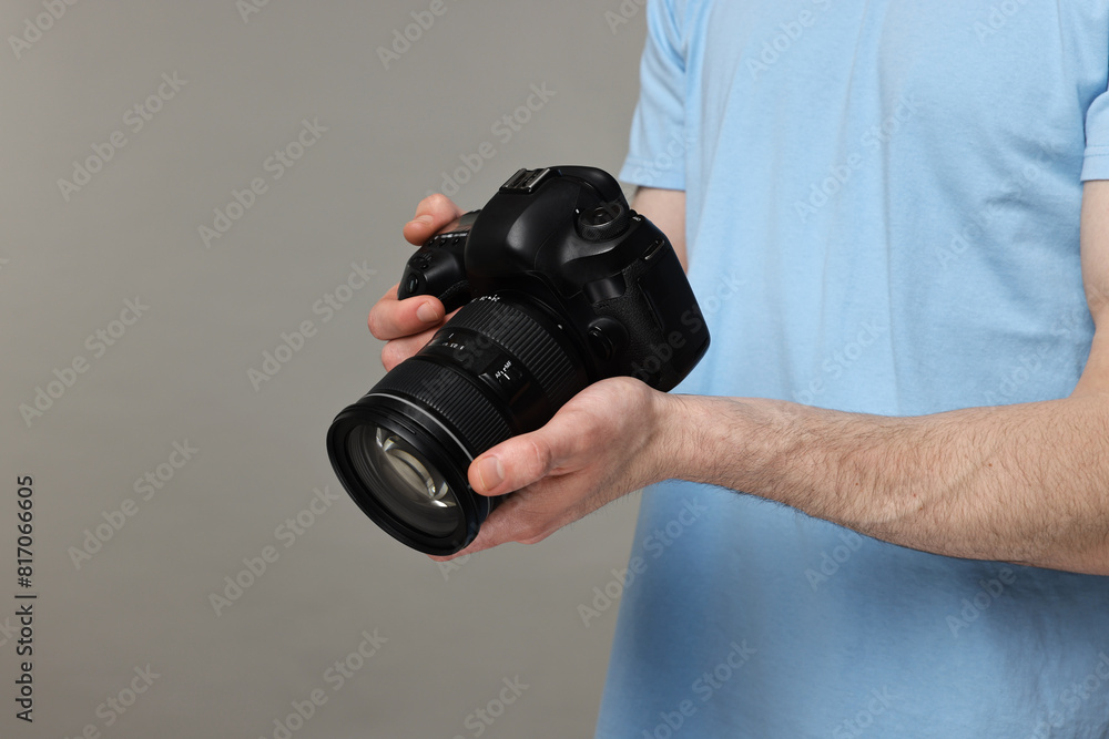 Photographer holding camera on grey background, closeup. Space for text Photographer holding camera on grey background, closeup. Space for text