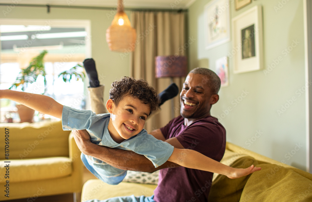 Joyful father playing airplane game with young son at home on couch Joyful father playing airplane game with young son at home on couch
