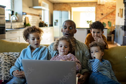 Happy diverse family enjoying time together with laptop at home photo