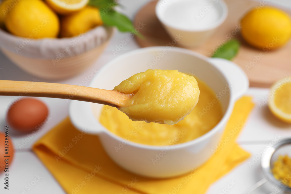 Taking delicious lemon curd from bowl at table, closeup Taking delicious lemon curd from bowl at table, closeup