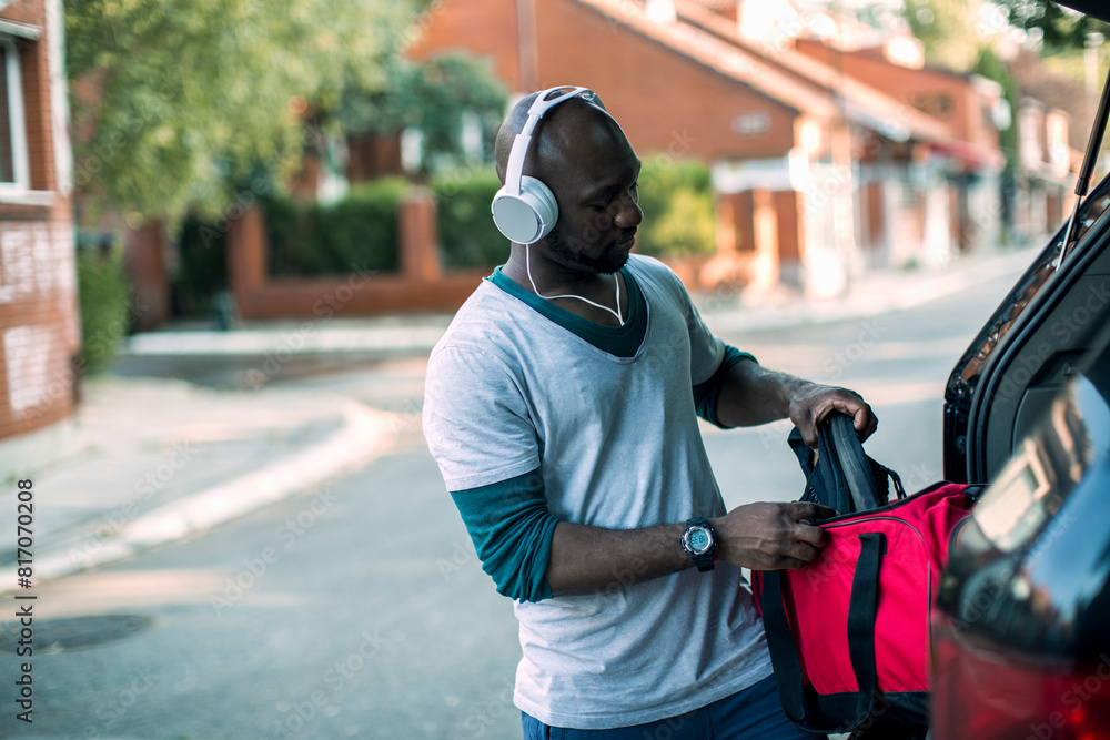 African American man packing sports bag in car trunk after workout African American man packing sports bag in car trunk after workout