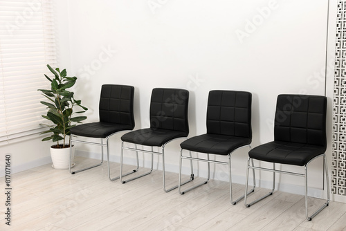 Many chairs near white wall in waiting area indoors