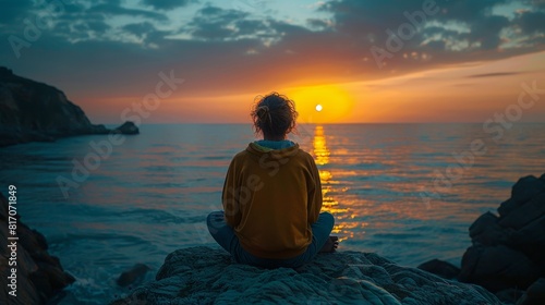 A person contemplatively watching the colors of sunrise over the ocean photo