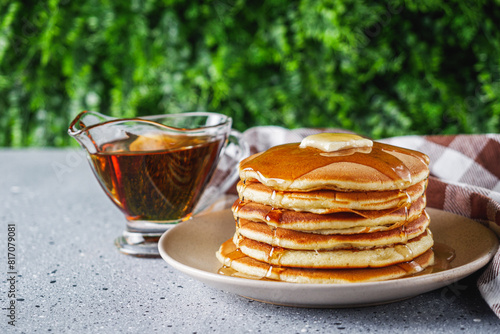 fresh tasty pancakes with maple syrup on a light stone background