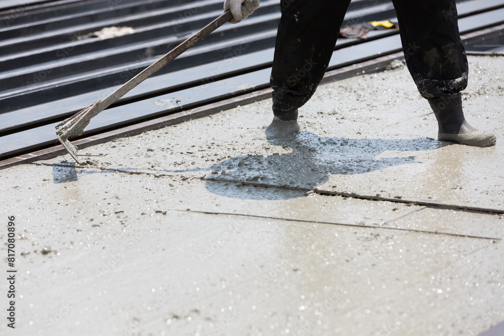 Construction worker spreading wet concrete pouring at precast concrete wall construction site. Worker or mason working or making smooth surface of concrete at site work Construction worker spreading wet concrete pouring at precast concrete wall construction site. Worker or mason working or making smooth surface of concrete at site work