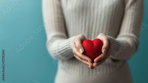 A woman s hands clasping a red heart symbolizing blood donation in honor of World Blood Donor Day with ample space for advertising purposes photo