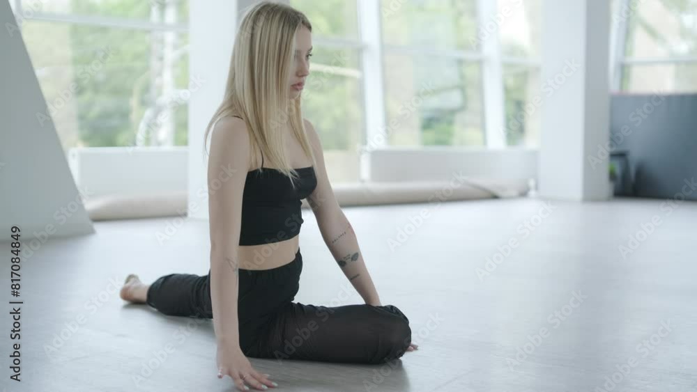 Fit girl in black clothes performing contemporary. Female dancer shows flowing motions, body and hands waves at white room. Modern ballet dance choreography. Young woman is moving smoothly Fit girl in black clothes performing contemporary. Female dancer shows flowing motions, body and hands waves at white room. Modern ballet dance choreography. Young woman is moving smoothly