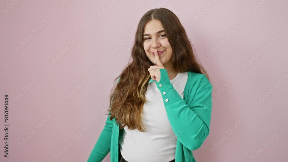 Shush! beautiful young hispanic woman confidently stands in silence, finger on lips gesturing a secret quiet. over a calm, isolated pink background. relax, stop talking, striking a silent pose. Shush! beautiful young hispanic woman confidently stands in silence, finger on lips gesturing a secret quiet. over a calm, isolated pink background. relax, stop talking, striking a silent pose.