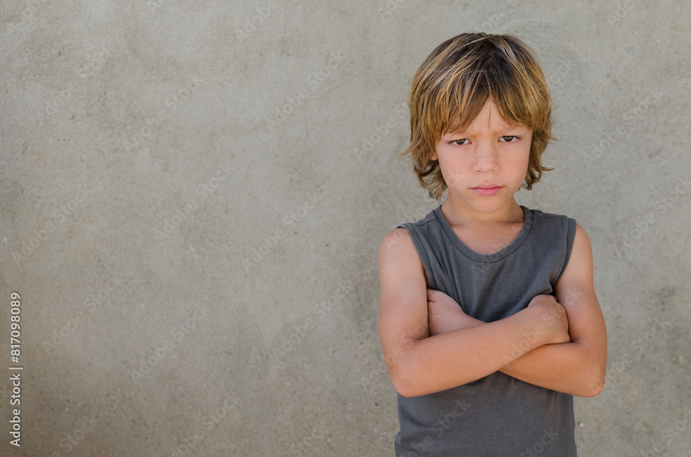 Horizontal photography of annoyed and unhappy caucasian blond kid standing with crossed arms and looking at camera. Family relations, social and psychologies issues concepts. Space for copy. Horizontal photography of annoyed and unhappy caucasian blond kid standing with crossed arms and looking at camera. Family relations, social and psychologies issues concepts. Space for copy.
