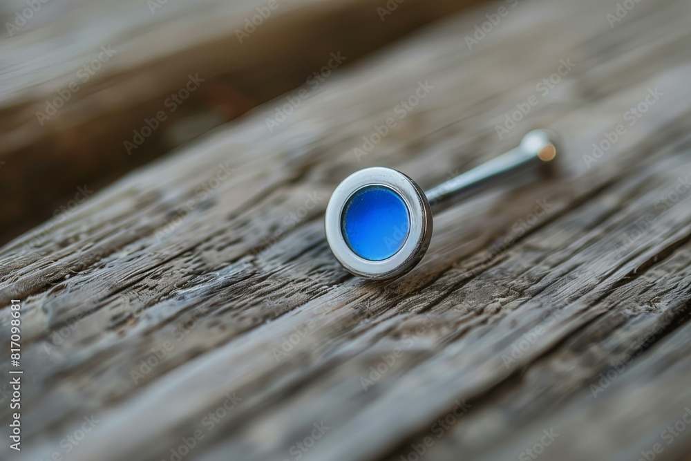 A small blue button on a wooden surface A small blue button on a wooden surface