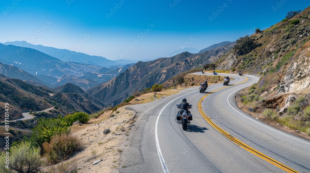 Motorcyclists navigating hairpin turns on a mountain pass road, with clear blue skies overhead.