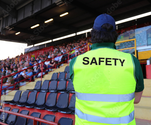 Canvas Print stadium steward with the phosphorescent jacket and the SAFETY writing who contro
