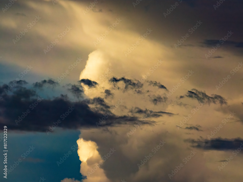Obraz premium Foreground cloud and cloudlets in silhouette, with larger clouds in the distance illuminated by the sun, on a summer evening in southwest Florida, for motifs of difference and transition