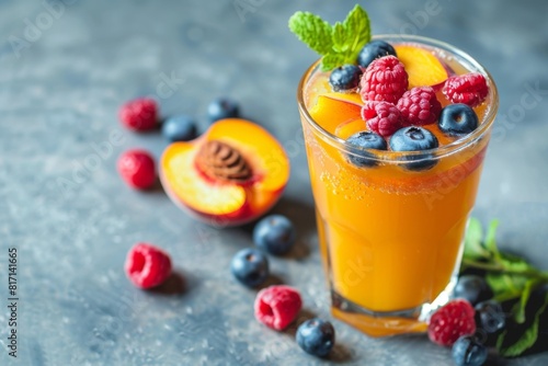 Refreshing drink made with orange juice, raspberries, blueberries, and a peach