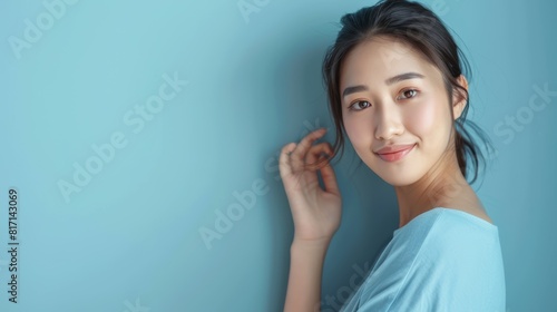 Young Asian woman smiling against blue background. Studio portrait with place for text. Beauty and lifestyle concept