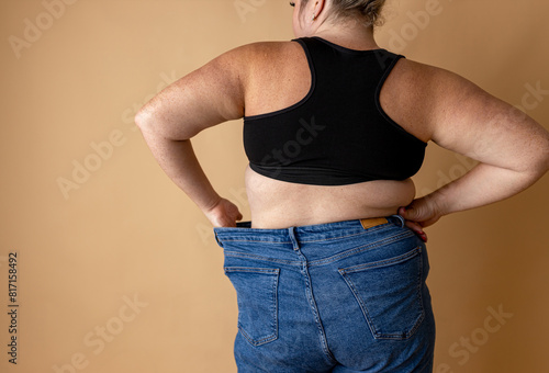 Close-up of belly and back rolls of plus size woman against beige background